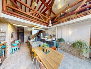 A spacious kitchen with modern appliances, a dining area with wooden furniture, and a stone wall. - Maifelder Wellness-Loft in Gappenach by Interhome (Gappenach)