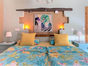 A bedroom with a bed, two nightstands, a wall-mounted painting, and a wooden headboard. - Maifelder Wellness-Loft in Gappenach by Interhome (Gappenach)