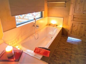 A bathroom with a bathtub, a window, and a towel rack. - Maifelder Wellness-Loft in Gappenach by Interhome (Gappenach)