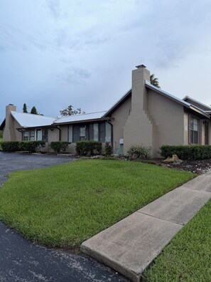 A single-story building with a flat roof, a front entrance, and a driveway leading to the parking area.