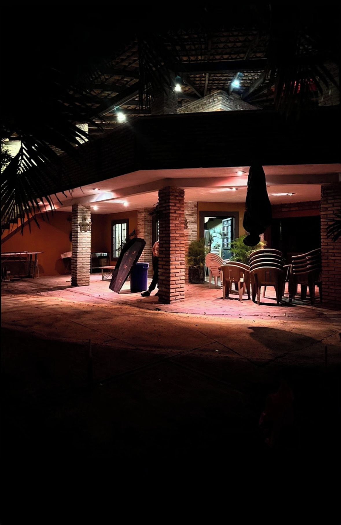 Un espacio al aire libre con una estructura de ladrillo, una mesa, sillas y un objeto colgante.
