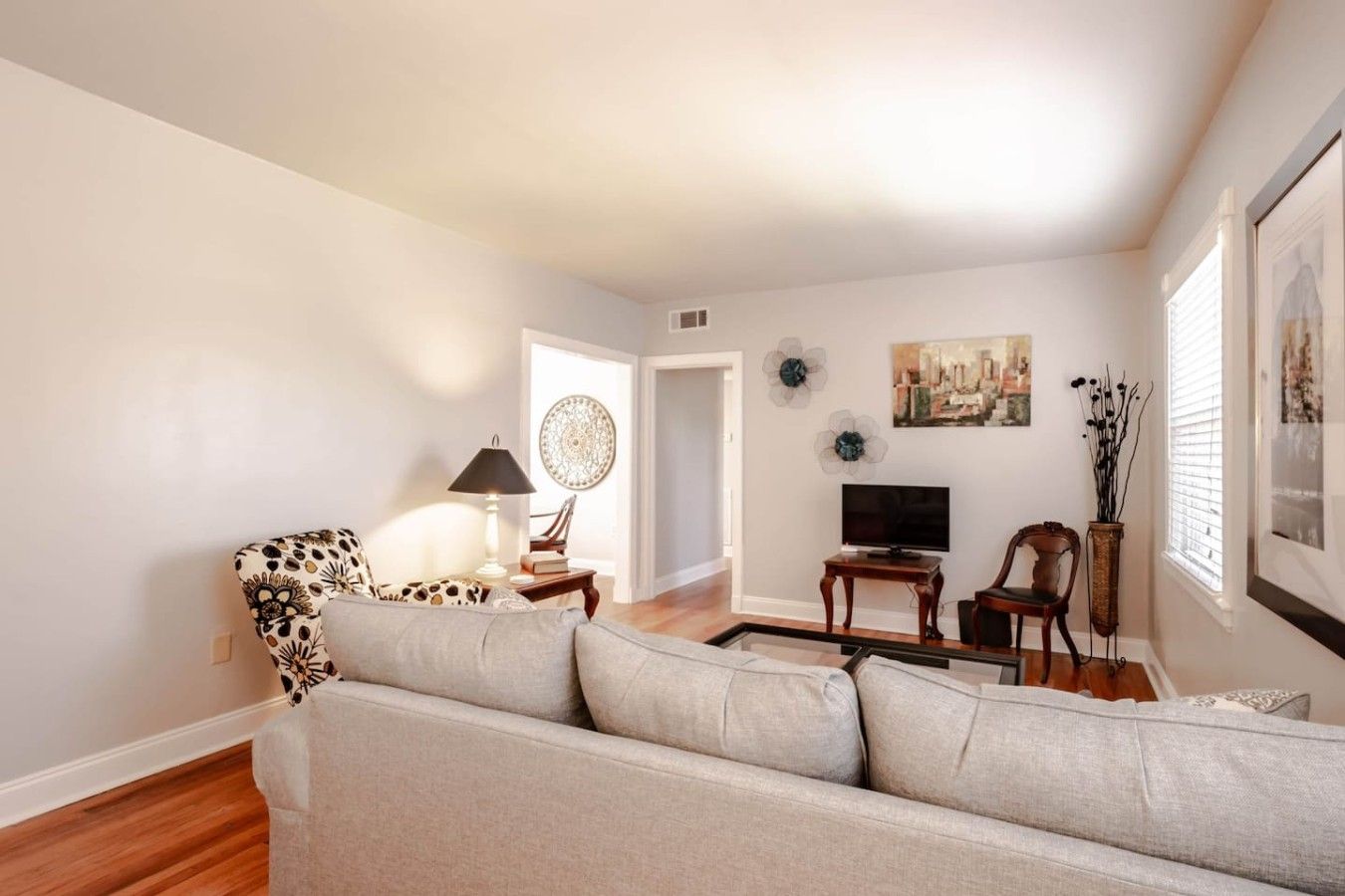 A living room with a sofa, a lamp, a television, and decorative items on the wall.