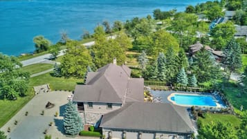 A residential property with a large house, a swimming pool, and a lake view.
