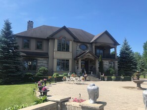 A large two-story house with a stone facade, multiple windows, and a front porch with outdoor seating.