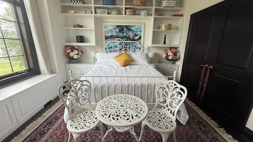 A bedroom with a bed, white furniture, a patterned rug, and a window with curtains.