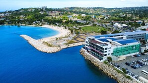 A coastal area with a beach, a marina, and a building with a parking lot. - The Bloom - Oceanfront King Suite (Montego Bay)