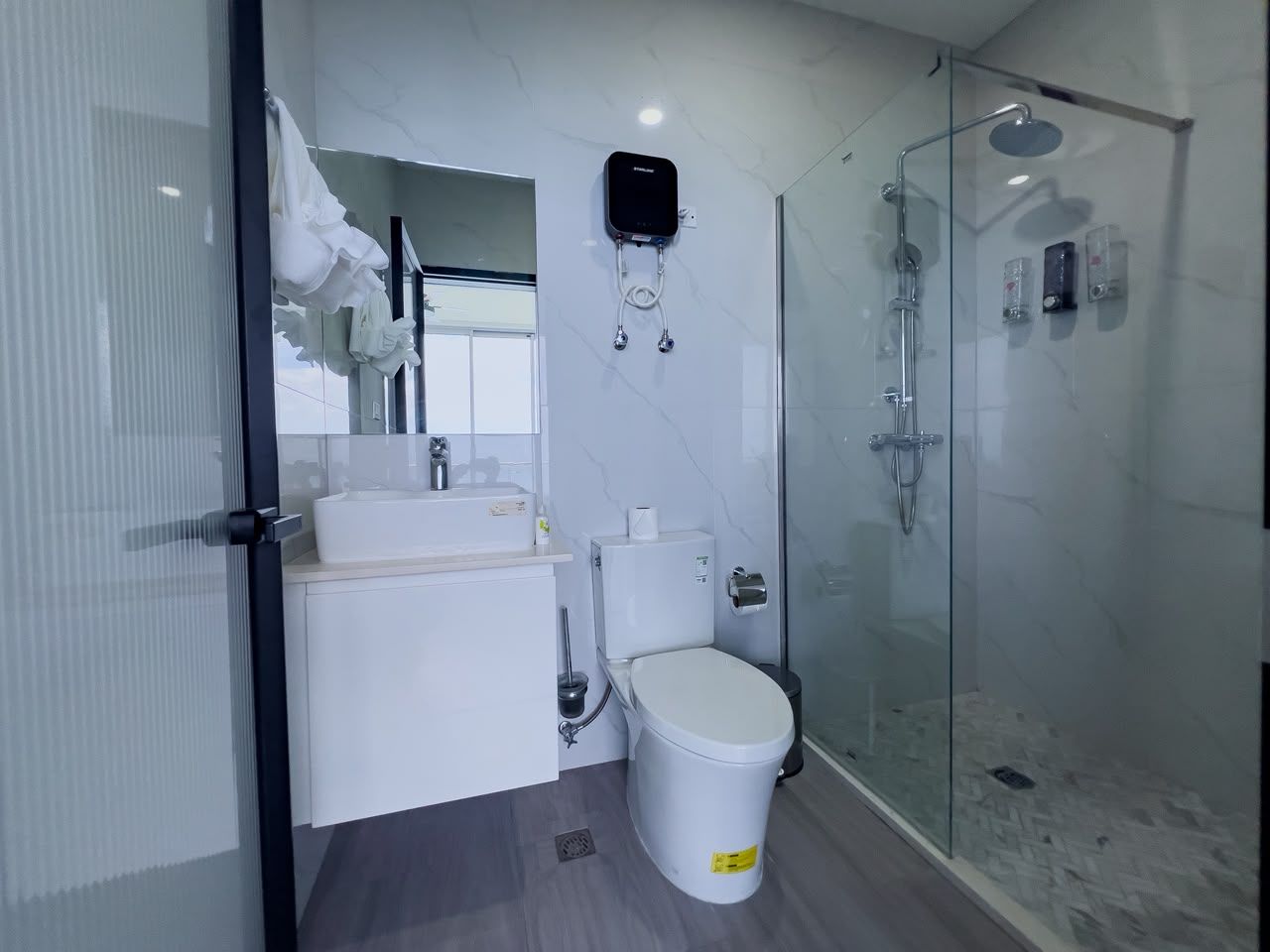 A modern bathroom with a glass shower enclosure, a toilet, and a sink.