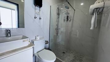 A modern bathroom with a glass-enclosed shower, a toilet, and a sink.