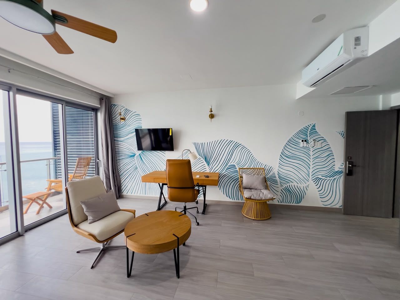 Sala de estar moderna com uma janela ampla, TV de tela plana e parede com padrão de folhagem.