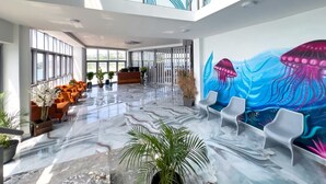 Um hall amplo com piso de mármore, áreas de estar e um balcão de recepção.