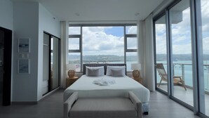 Quarto espaçoso com uma cama grande, varanda com vista para o mar e uma porta deslizante que dá para outro cômodo.
