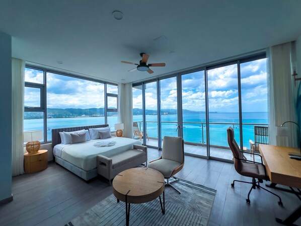 Habitación de hotel moderna con una cama grande, un escritorio, una silla y vistas al mar.