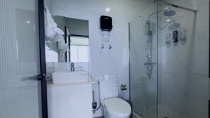 Casa de banho moderna com cabine de duche em vidro, sanita e lavatório.