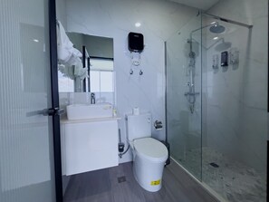Un baño moderno con cabina de ducha de vidrio, inodoro y lavamanos.