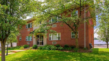 A two-story brick building with a front entrance, a small porch, and a well-maintained lawn.