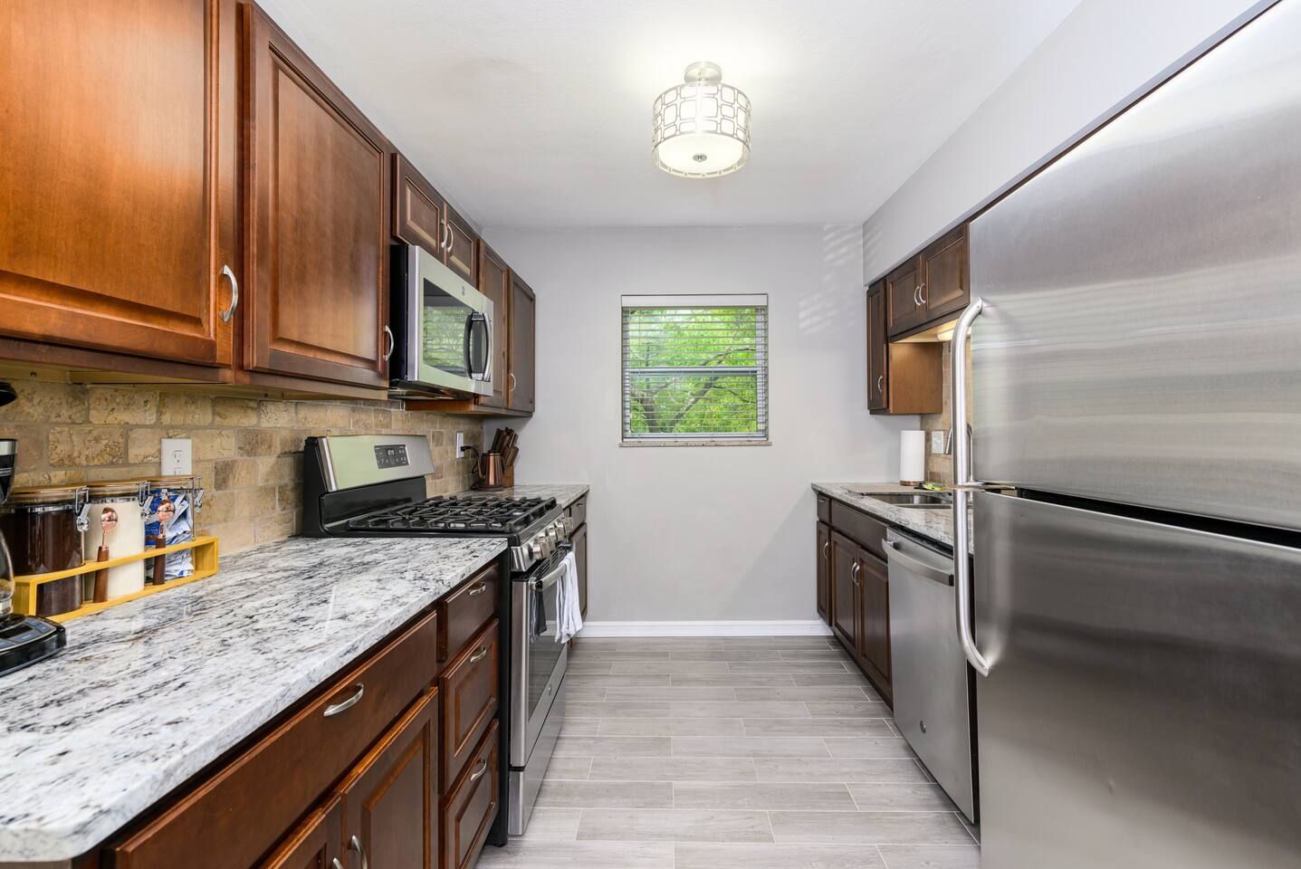 A kitchen with wooden cabinets, a stainless steel refrigerator, a built-in oven, and a microwave.