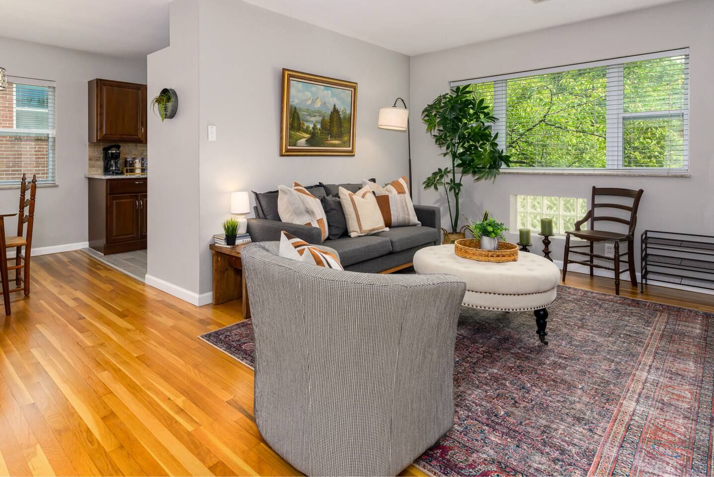 A living room with a grey sofa, a coffee table, a rug, and a painting on the wall.