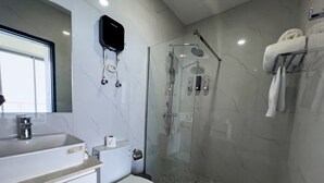 Un bany modern amb dutxa d'ús de vidre, un vàter i un lavabo.
