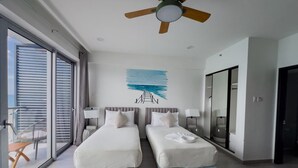 Habitació d'hotel amb dos llits, un ventilador de sostre, una finestra gran i vistes a l'exterior.