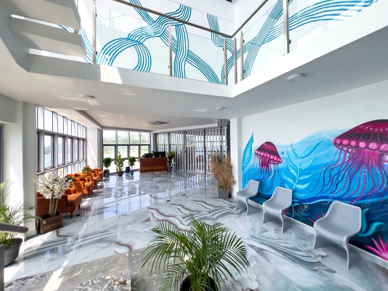 A spacious lobby with a marble floor, seating areas, and a reception desk.