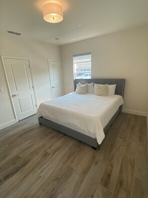 Quarto com cama grande, janela e porta.