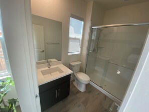 Ein Badezimmer mit Dusche, Toilette, Waschbecken und Spiegel.