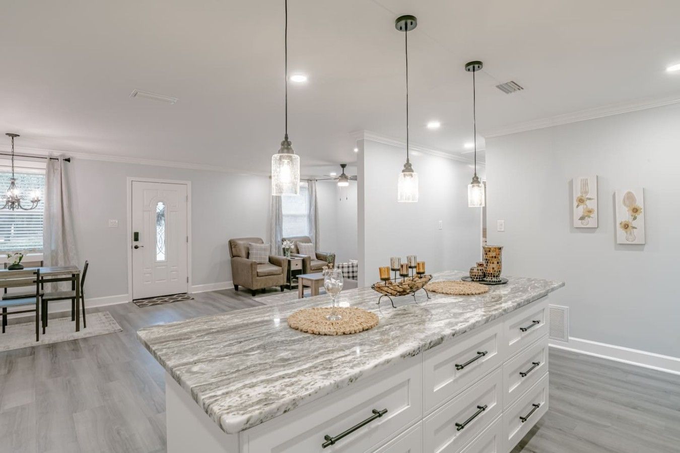 Una cocina moderna con encimera de mármol, iluminación colgante y comedor con mesa y sillas.