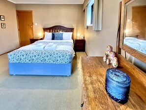 Una habitació d'hotel amb un llit gran, una nitzeta de fusta i un vas decoratiu.