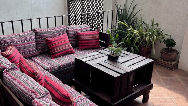 Uma varanda com um conjunto de sofás, uma mesa de madeira e plantas em vasos.