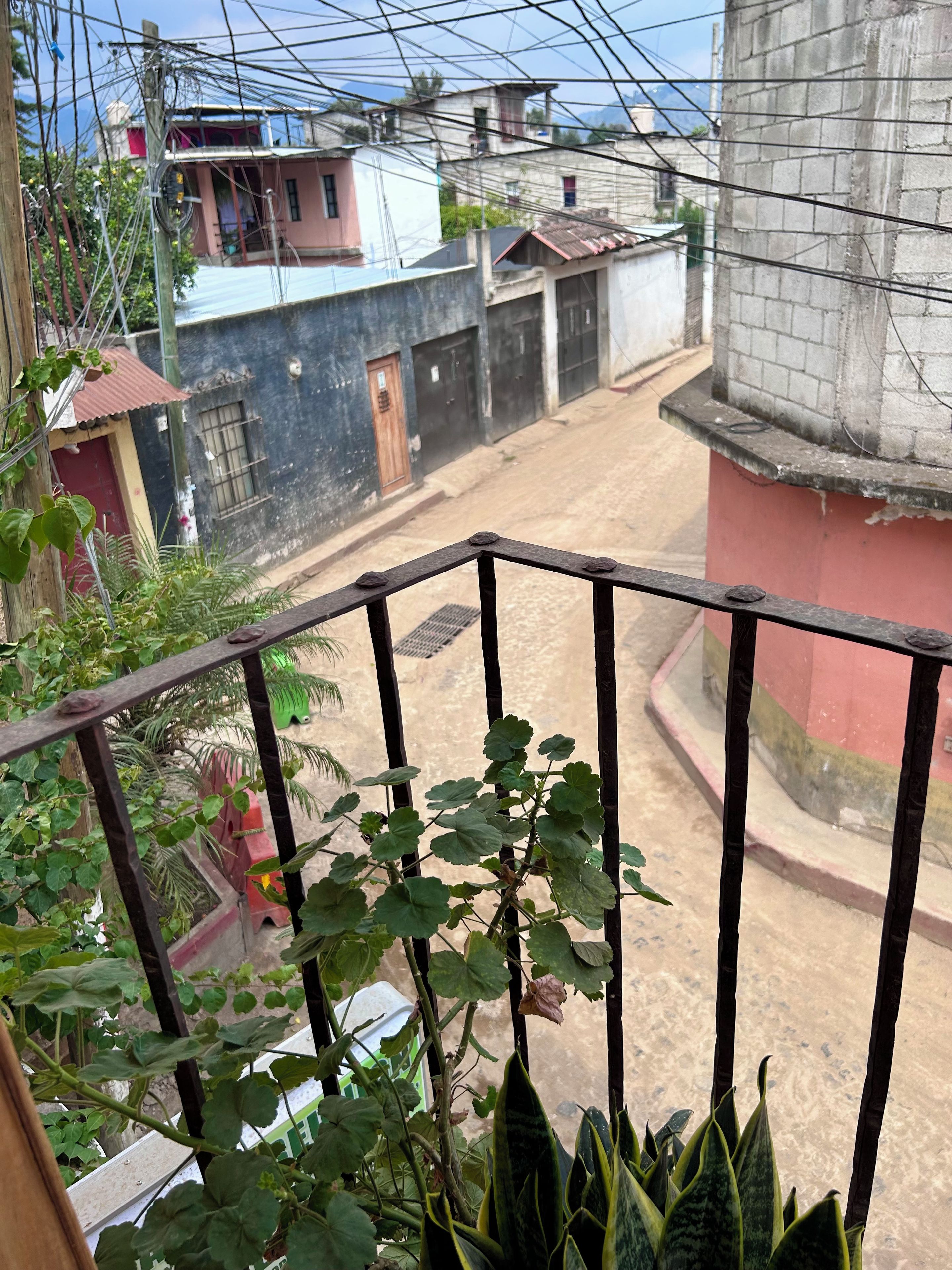 A balcony with a view of a residential street, including houses and a clear sky.