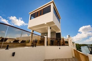 A modern two-story building with a balcony overlooking a body of water. - Villa Camila is a stylish, modern one-bedroom apartment, centrally located. (Cooper Jack Bay Settlement, Providenciales)