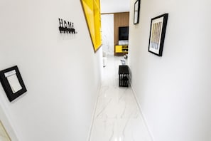 Un couloir doté d’un sol en marbre, d’un mur peint dans une teinte jaune et d’un banc noir.