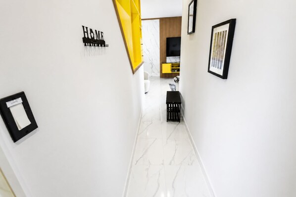 A hallway with a marble floor, a yellow accent wall, and a black bench. - Villa Camila is a stylish, modern one-bedroom apartment, centrally located. (Cooper Jack Bay Settlement, Providenciales)