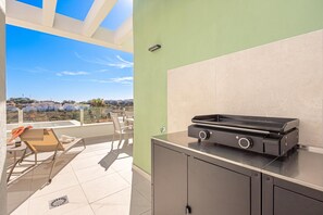 Ein Balkon mit Grill, Stuhl und Blick auf eine Landschaft.
