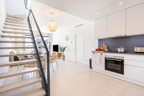 Eine moderne Küche mit Backofen, eine Essecke mit Tisch und Stühlen sowie eine Treppe zu einer weiteren Ebene.