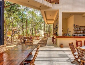 An outdoor dining area with wooden tables and chairs, surrounded by trees. - Peaceful Luxury Ground-Floor Retreat, 2BR, 2BA, Selva Norte Tulum (Tulum)
