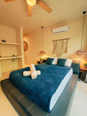 A modern hotel room with a large bed, a ceiling fan, a wall-mounted air conditioner, and a bedside table with a lamp. - Peaceful Luxury Ground-Floor Retreat, 2BR, 2BA, Selva Norte Tulum (Tulum)