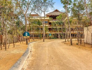 A dirt road leading to a building with a thatched roof, surrounded by trees. - Peaceful Luxury Ground-Floor Retreat, 2BR, 2BA, Selva Norte Tulum (Tulum)
