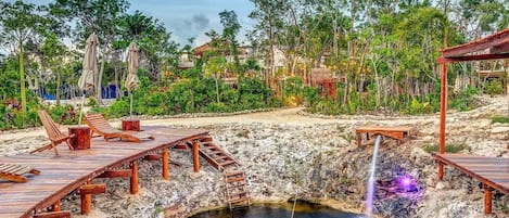 A natural hot spring with wooden walkways and lounge chairs.