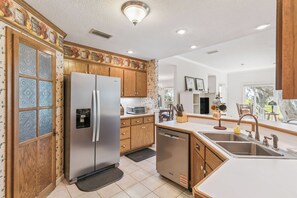 A modern kitchen with a stainless steel refrigerator, wooden cabinets, a dishwasher, and a sink with a faucet. - Heron's Perch - Marsh Front (Pet Friendly) (Waverly)