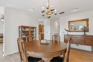 A dining room with a wooden table, chairs, a chandelier, a cabinet, and a mirror. - Heron's Perch - Marsh Front (Pet Friendly) (Waverly)