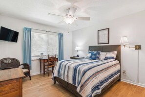 A bedroom with a bed, a chair, a desk, a ceiling fan, a TV, and a window with curtains. - Heron's Perch - Marsh Front (Pet Friendly) (Waverly)