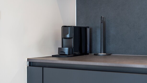 Eine moderne Kaffeemaschine und ein schlanker Gegenstand auf einer Arbeitsplatte.