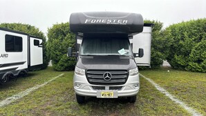 A white camper van with a black camper shell labeled 'FORESTER BY FOREST RIVER' parked on grass with trees in the background. - Luxury Mercedes 25 Foot RV w/ Full Bathroom + WiF/TV close to the Poconos (Blairstown)