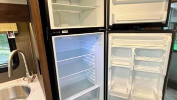 Una cocina con un refrigerador de dos puertas, un lavamanos de acero inoxidable y gabinetes de madera.