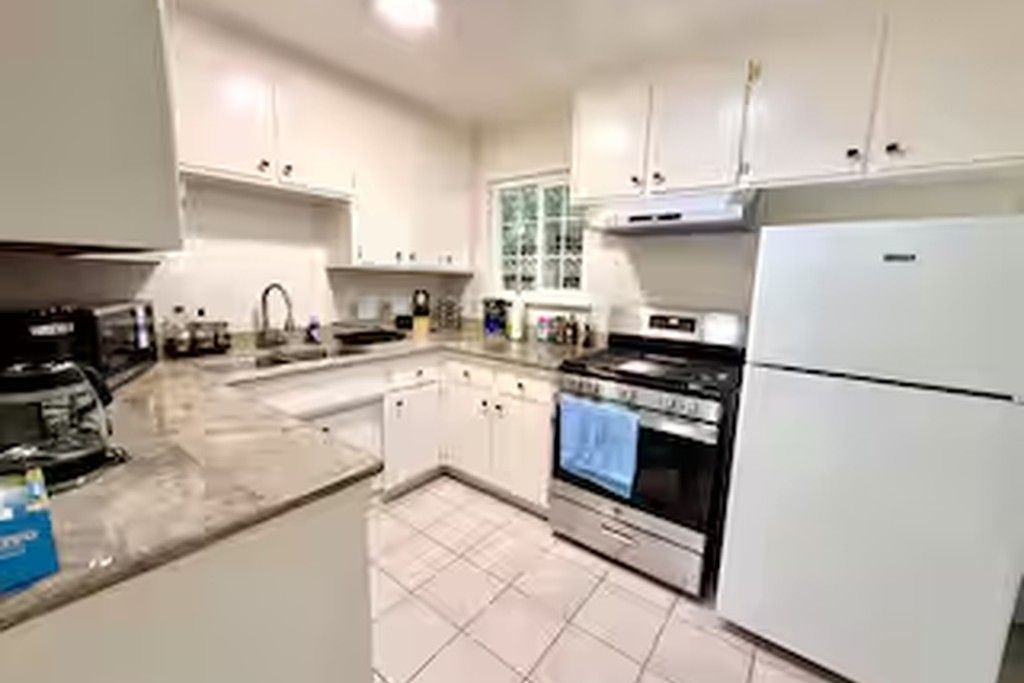 A kitchen with white cabinets, a stove, and a refrigerator.