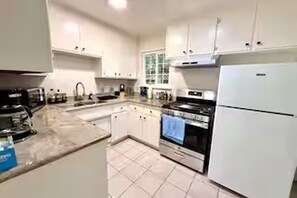 Eine Küche mit weißen Schränken, einem Herd und einem Kühlschrank.