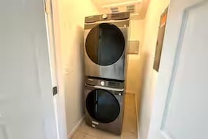 Een kleine wasruimte met twee gestapelde wasmachines.