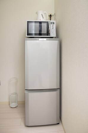 A white refrigerator with a microwave on top, a small white basket, and a clear glass. - Biancolina (Fukuoka City)