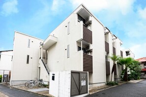 A modern building with a staircase leading to an upper level, a gated entrance, and a bicycle parked outside. - Biancolina (Fukuoka City)